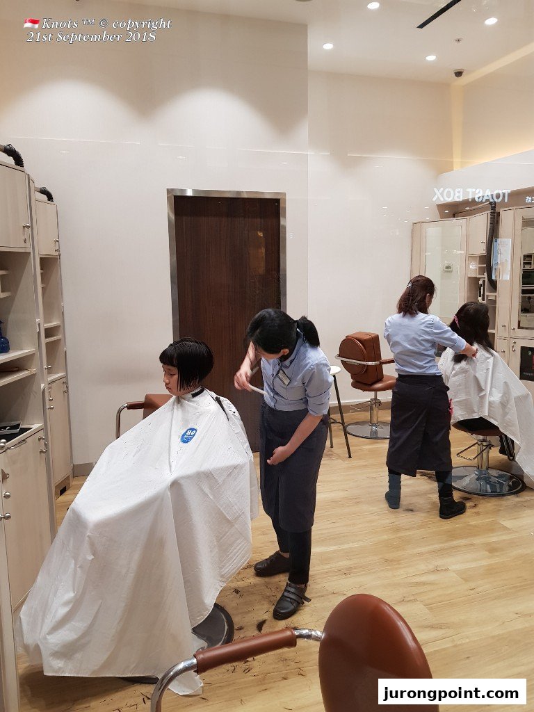 Customers receive efficient haircuts from stylists inside QB House.