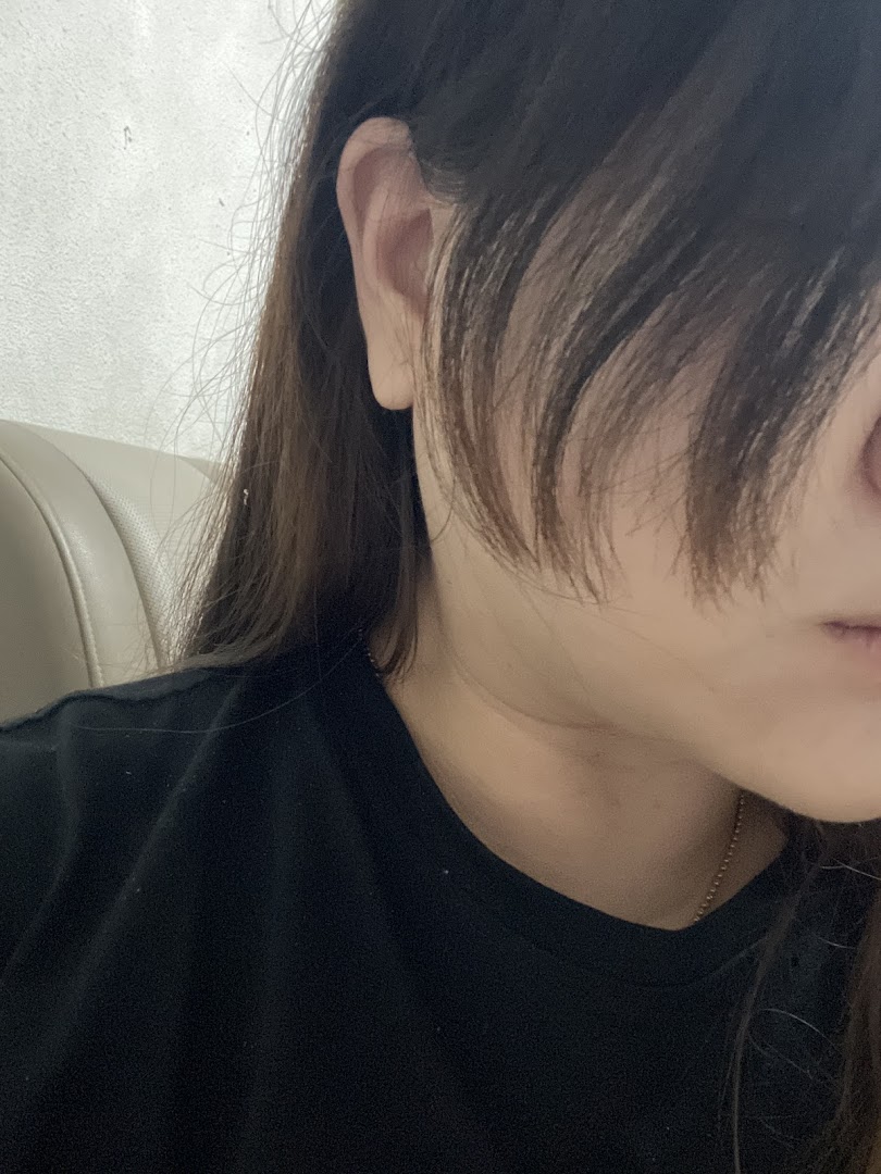 Close-up of a person's ear, hair, and shoulder, possibly inside a salon.