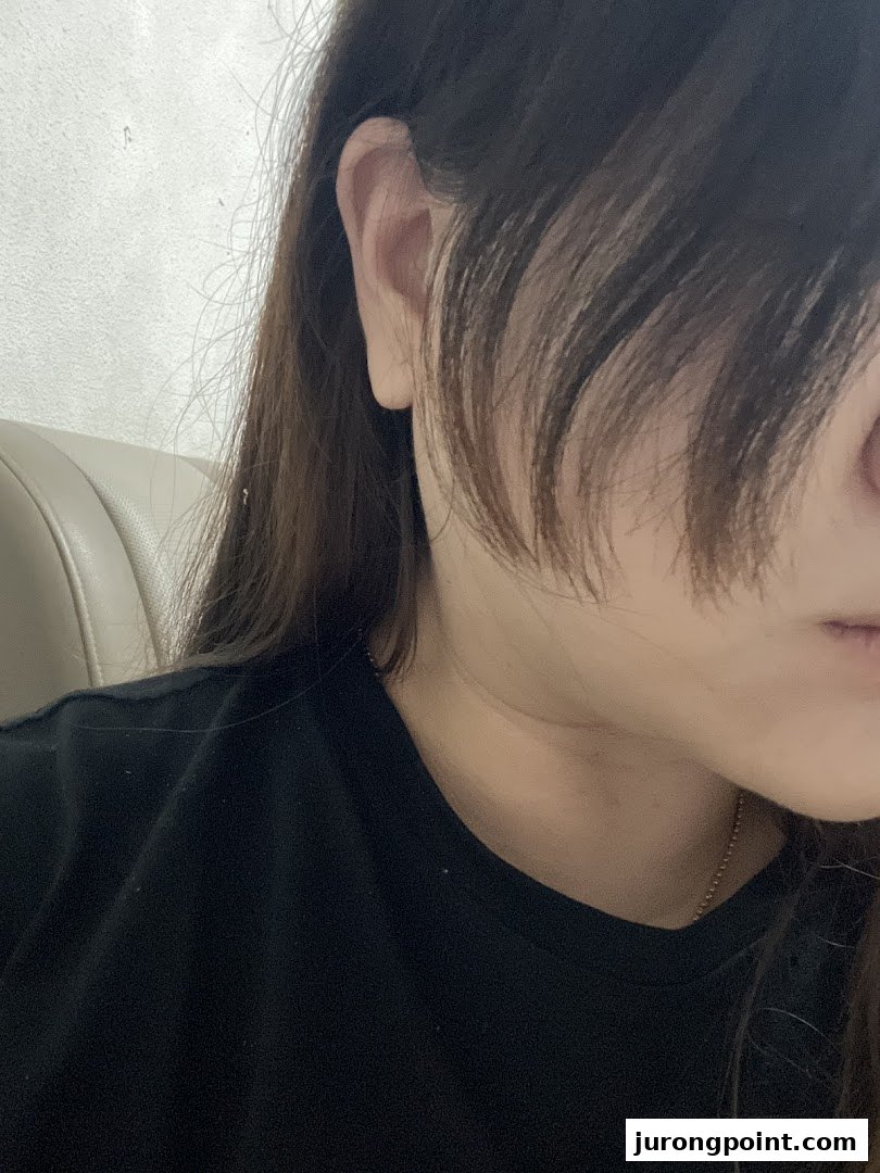 Close-up of a person's ear, hair, and shoulder, possibly inside a salon.
