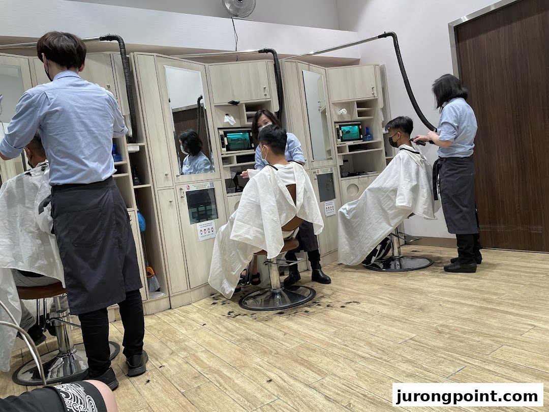 Customers receive quick haircuts from barbers in a clean, modern salon interior.