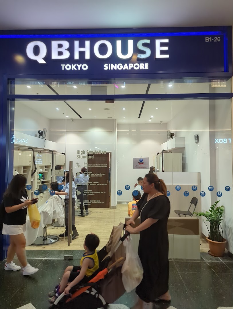 The storefront of QB House, a hair salon, with customers inside and outside.