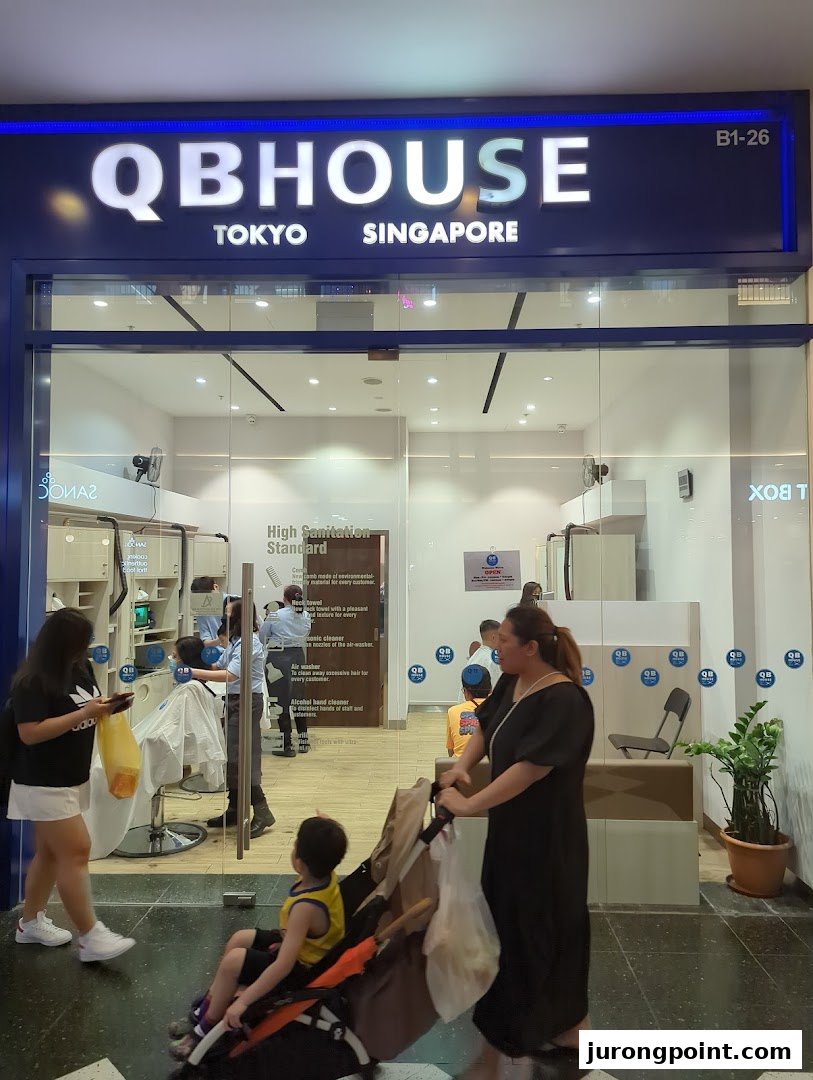 The storefront of QB House, a hair salon, with customers inside and outside.