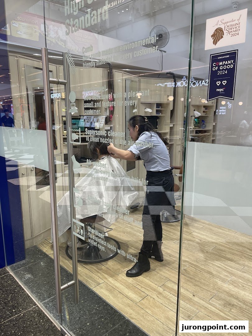 A stylist cuts a customer's hair inside QB House, visible through the glass entrance.