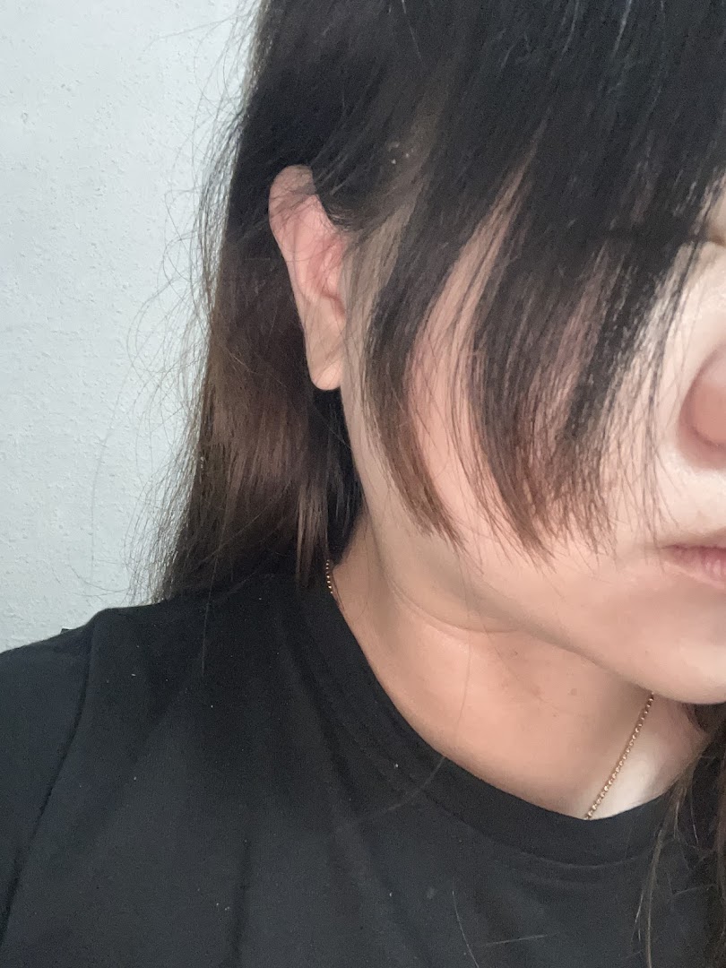 Close-up of a person's ear and dark hair, suggesting a focus on hair services.