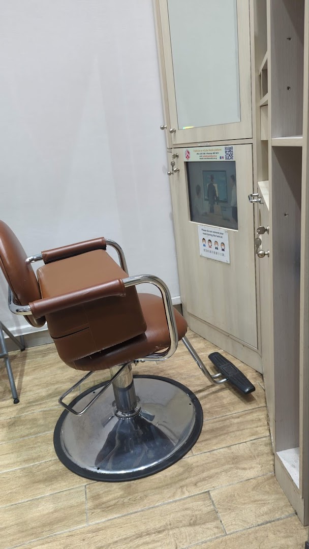 An interior view of QB House, featuring a brown styling chair and a station with a mirror and screen.