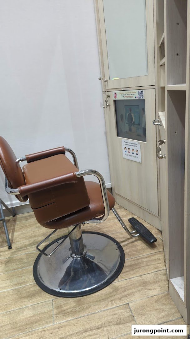 An interior view of QB House, featuring a brown styling chair and a station with a mirror and screen.