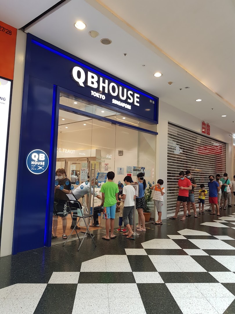 The storefront of QB House, a hair salon, with customers queuing outside.