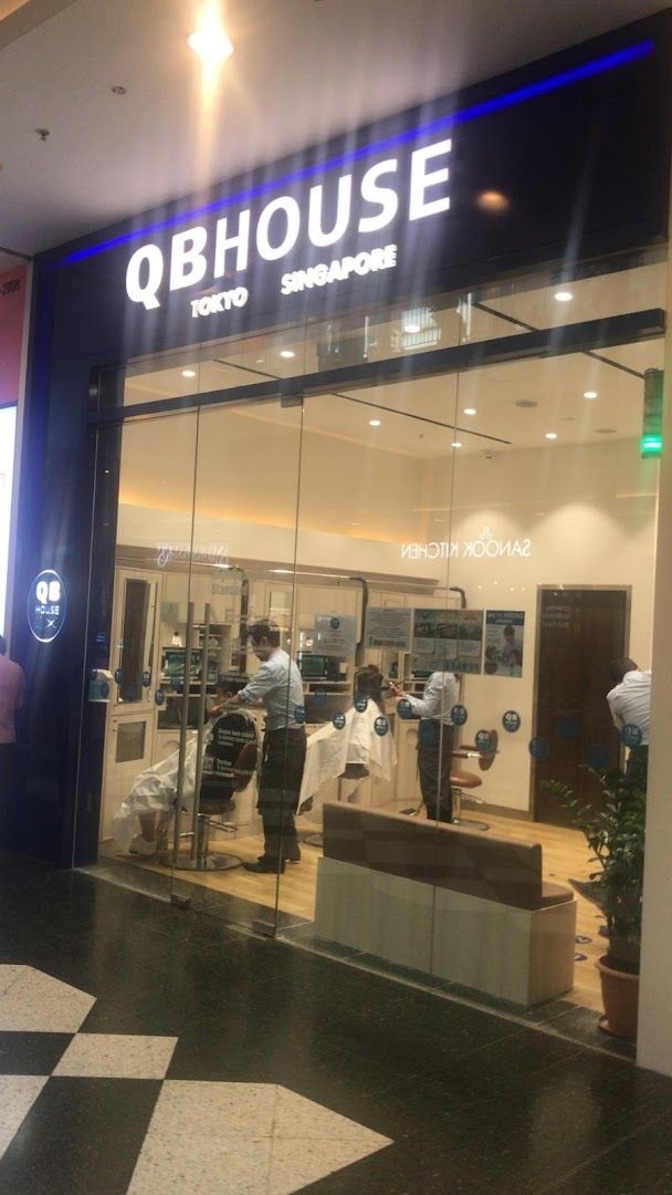 The storefront of QB House, a barbershop, with customers receiving haircuts inside.