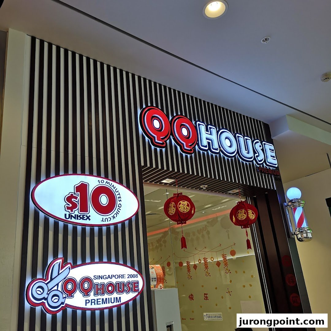 The illuminated storefront of QQ House, a hair salon offering quick unisex cuts.