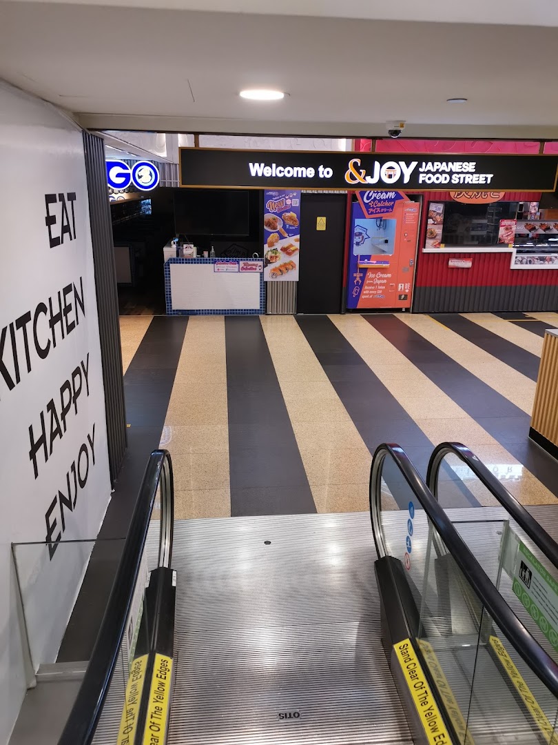 Entrance to &JOY Japanese Food Street from an escalator, featuring various food stalls.