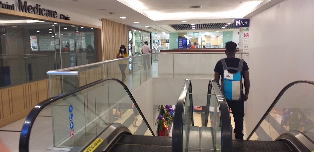 View of an escalator in a shopping mall with clinics and shops visible on the upper level.