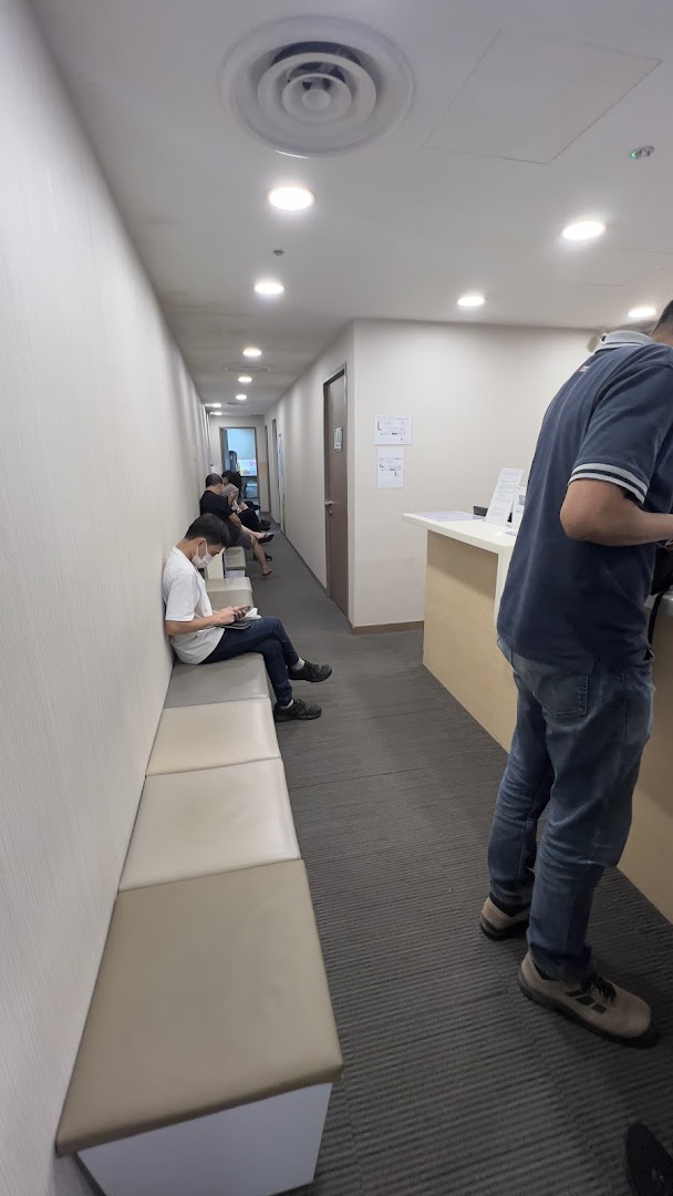 Patients wait in a well-lit corridor with a reception desk at Raffles Medical.