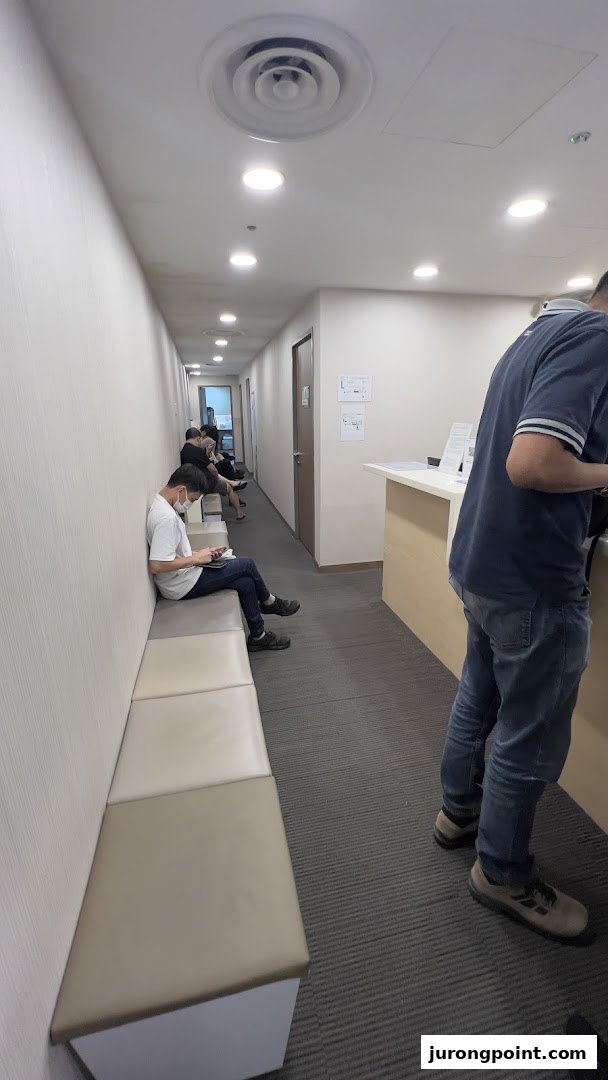 Patients wait in a well-lit corridor with a reception desk at Raffles Medical.