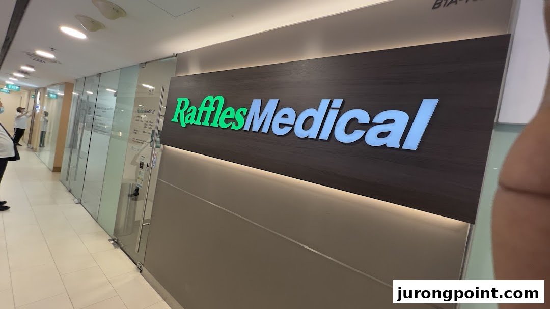 The illuminated sign and glass entrance of Raffles Medical clinic in a shopping mall.