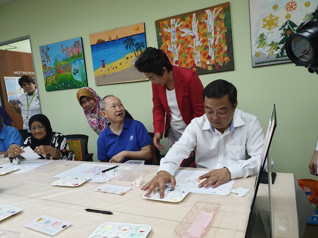 Participants engage in an art activity, painting at tables with palettes, surrounded by colorful artworks.