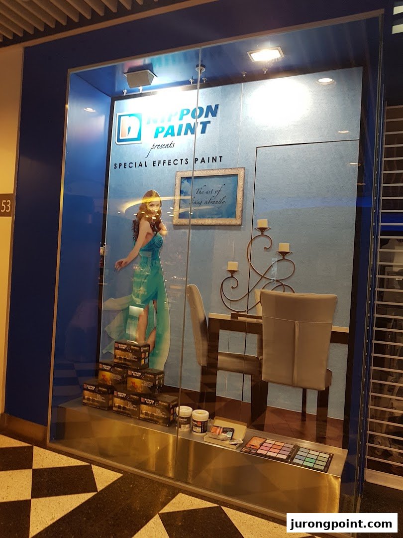 A display window for Nippon Paint showcasing special effects paint, featuring a model, furniture, and product samples.