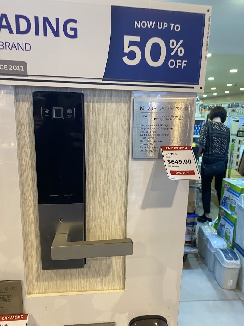A smart door lock display with a promotional sign for up to 50% off at Selffix DIY.