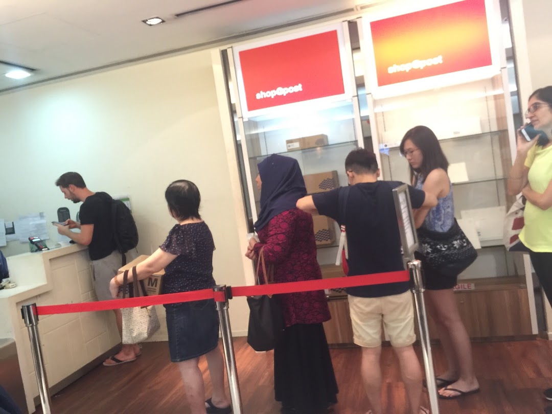 Customers queueing at service counters inside the Singapore Post Jurong Point branch.