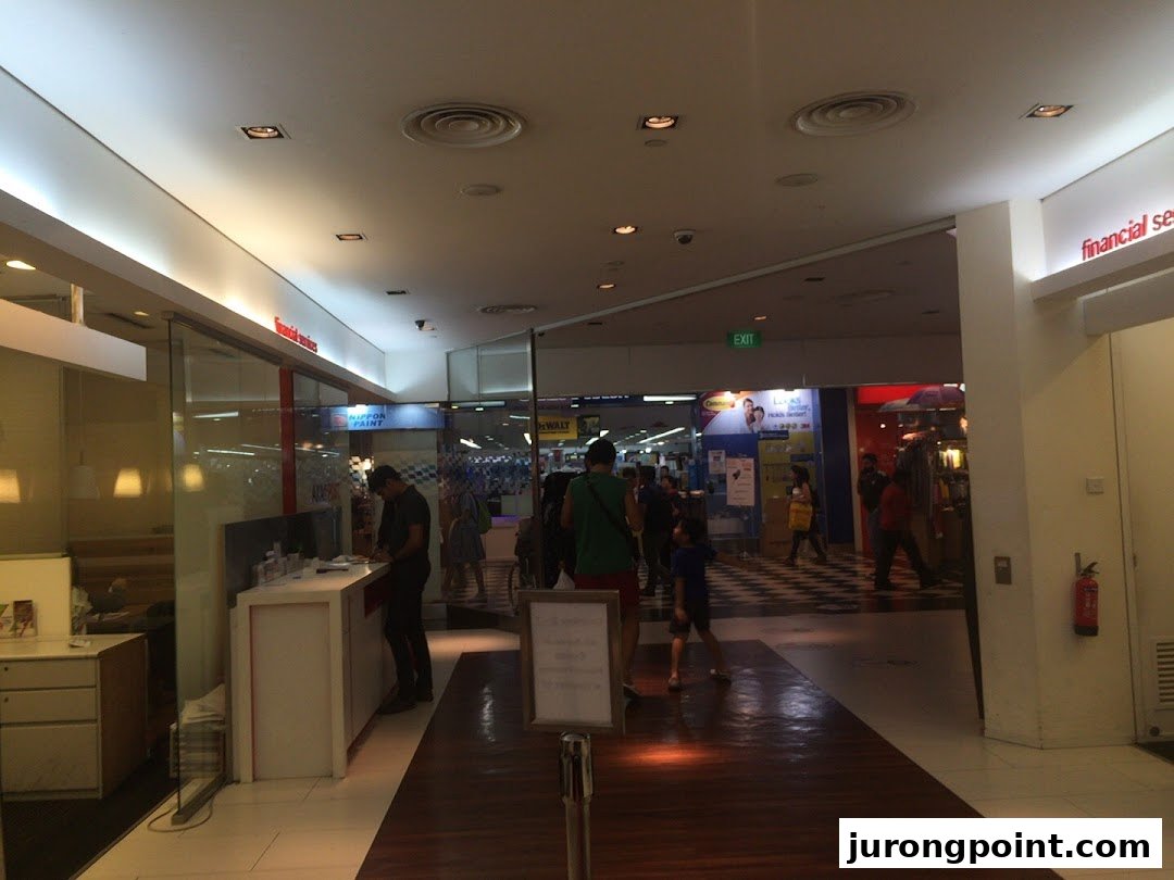 Interior view of a mall corridor showing the Singapore Post branch entrance and shoppers.