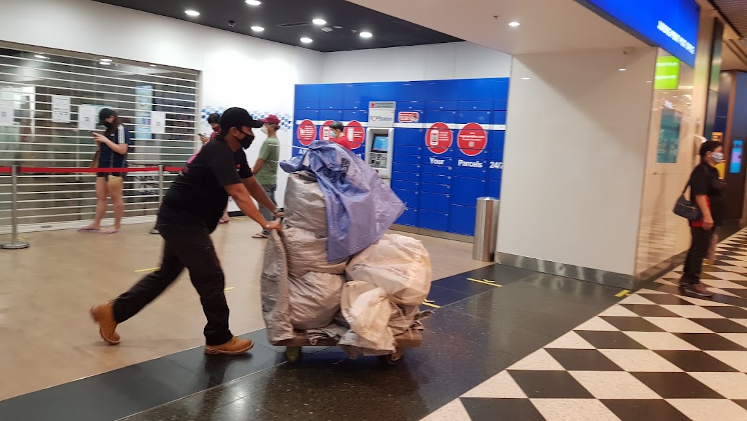 A person pushes a cart of parcels past Singapore Post's POPStation lockers in a mall.