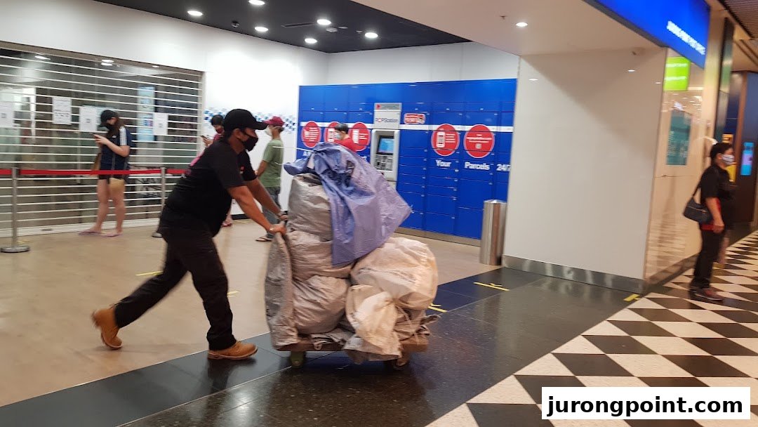 A person pushes a cart of parcels past Singapore Post's POPStation lockers in a mall.