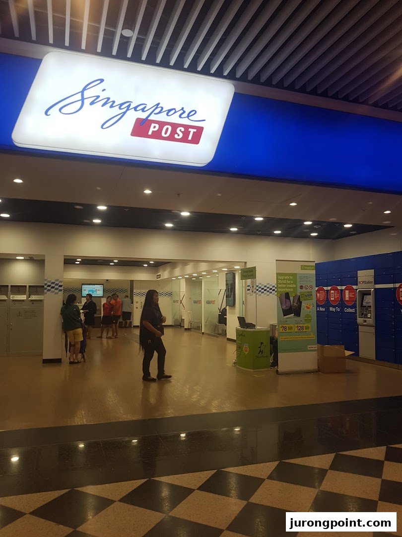 The brightly lit entrance and interior of a Singapore Post branch, showing service areas and customers.