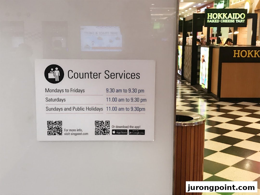 A sign for Singapore Post's counter services with operating hours and QR codes, set against a mall interior.