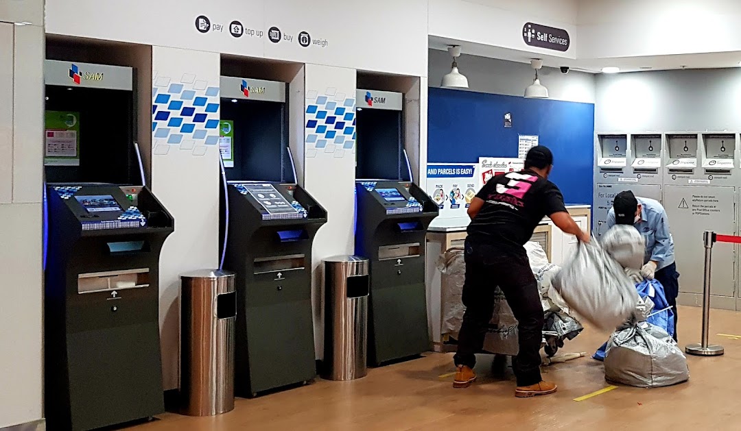 Interior view of Singapore Post's self-service area with SAM machines and staff handling parcels.