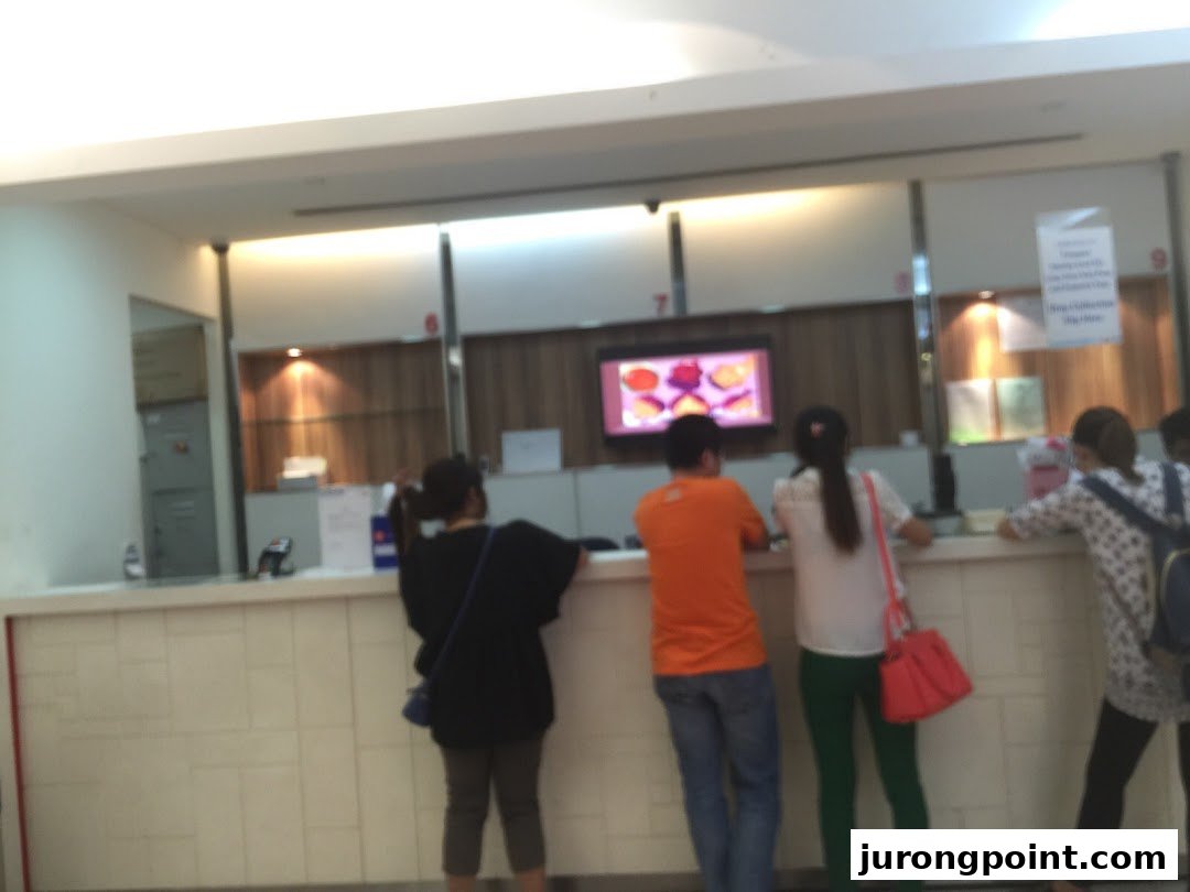 Customers are seen at the service counter of Singapore Post, with staff assisting them.