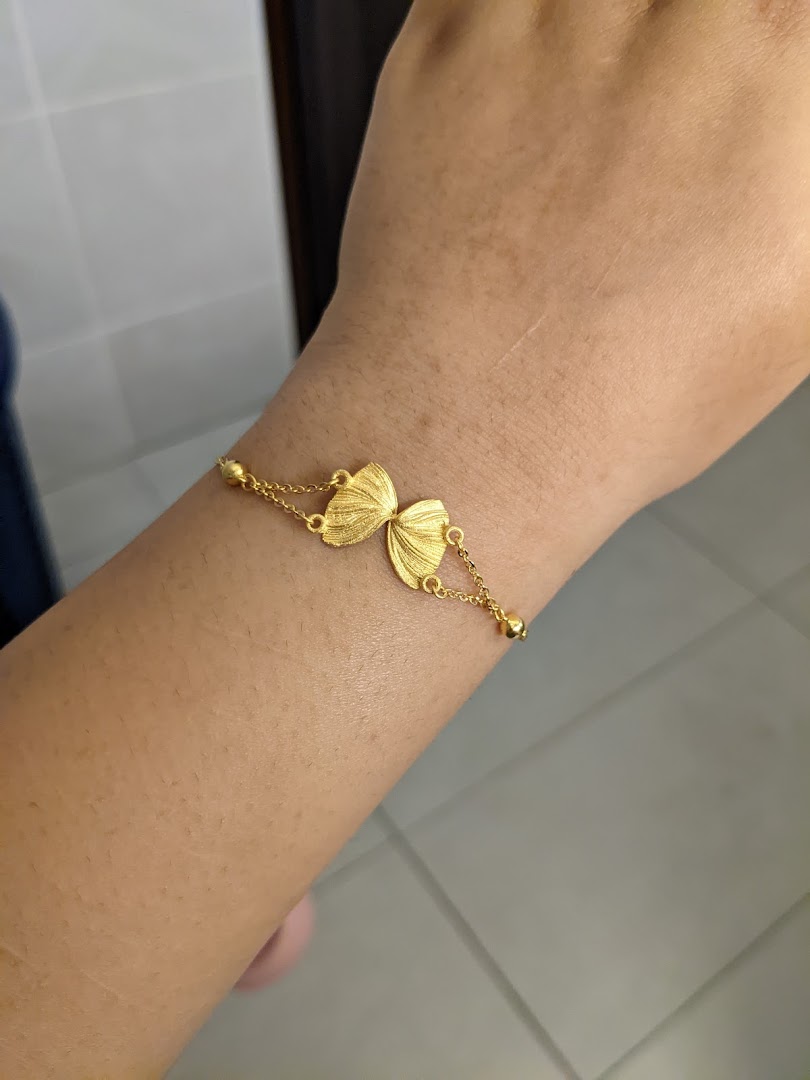 A person's arm adorned with a delicate gold butterfly bracelet from SK Gold.