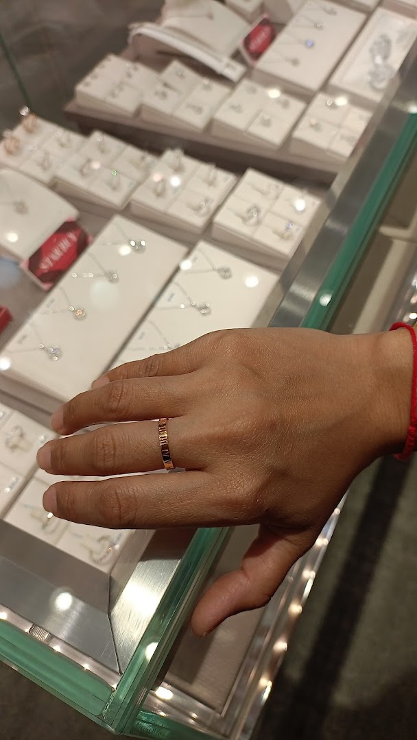 A hand wearing a ring, resting on a glass display case filled with various jewelry pieces.