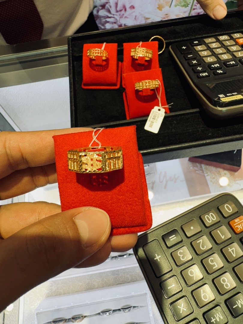 A close-up of gold rings, including an abacus design, displayed with a calculator in a jewelry shop.