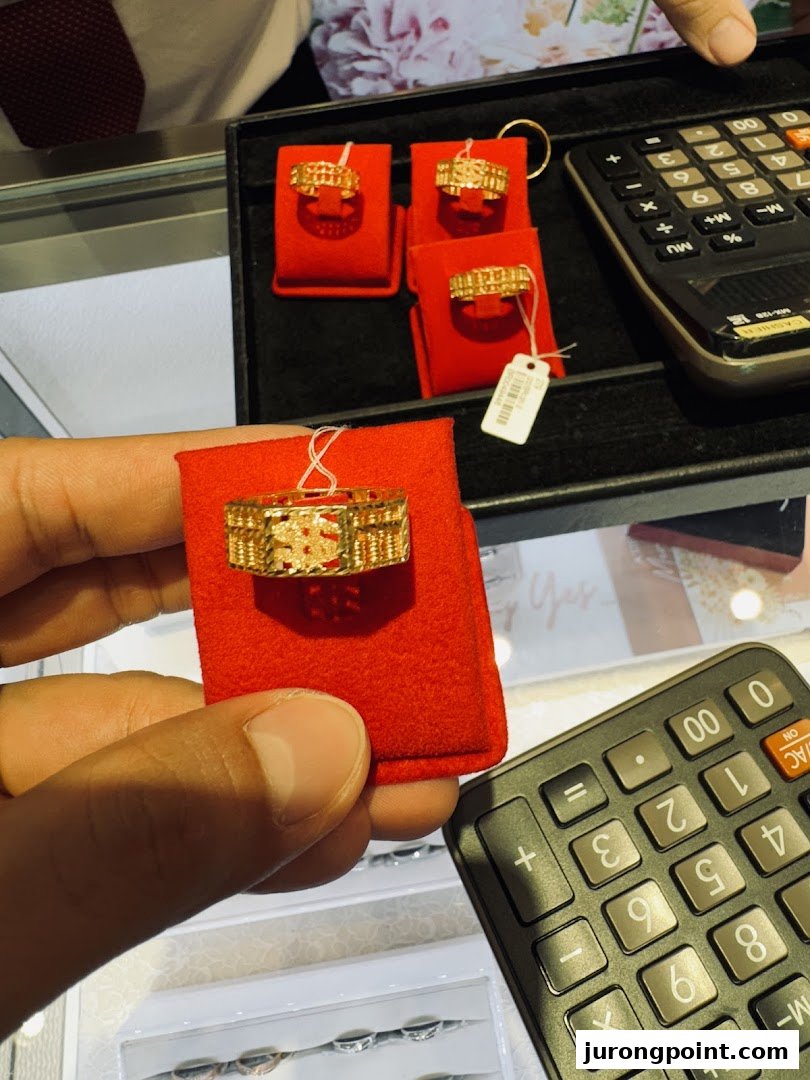 A close-up of gold rings, including an abacus design, displayed with a calculator in a jewelry shop.
