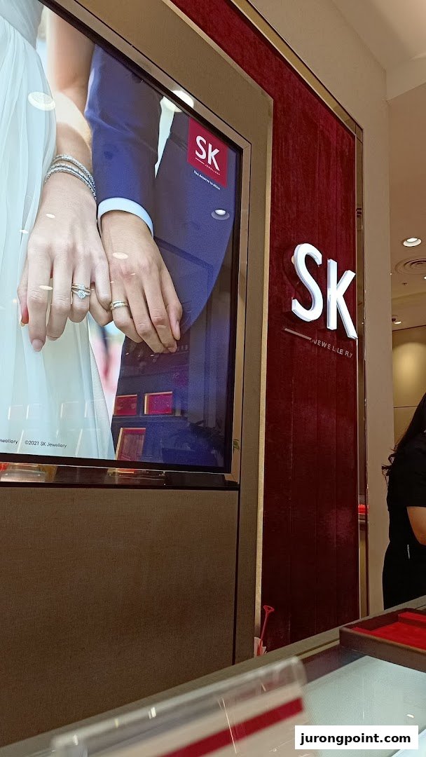A digital display showcasing wedding rings and the SK Jewellery logo inside the store.