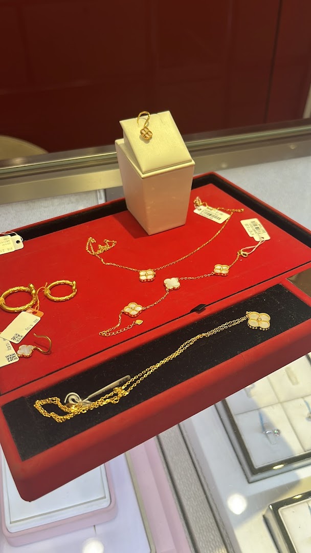 Close-up of exquisite gold necklaces and earrings with clover designs displayed on a red velvet tray.
