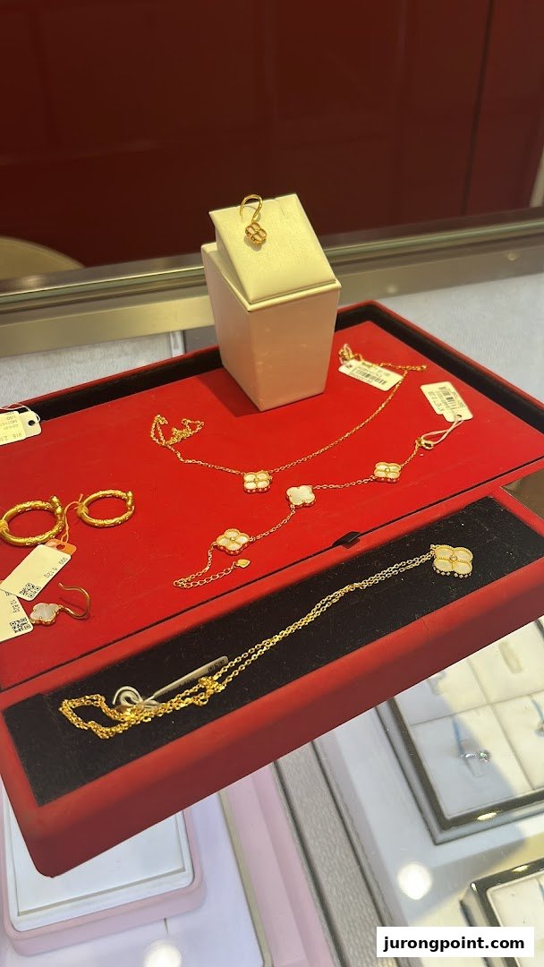Close-up of exquisite gold necklaces and earrings with clover designs displayed on a red velvet tray.