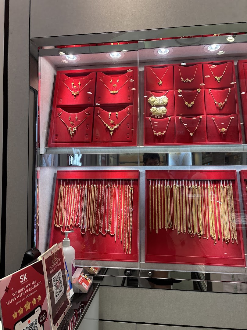 A display case inside SK Gold showcasing a variety of intricate gold necklaces and pendants on red velvet.