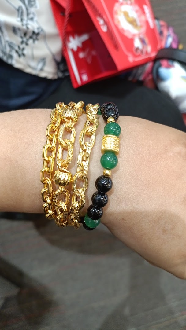 A person's wrist adorned with multiple gold chain bracelets and a beaded bracelet.