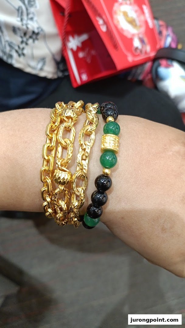 A person's wrist adorned with multiple gold chain bracelets and a beaded bracelet.