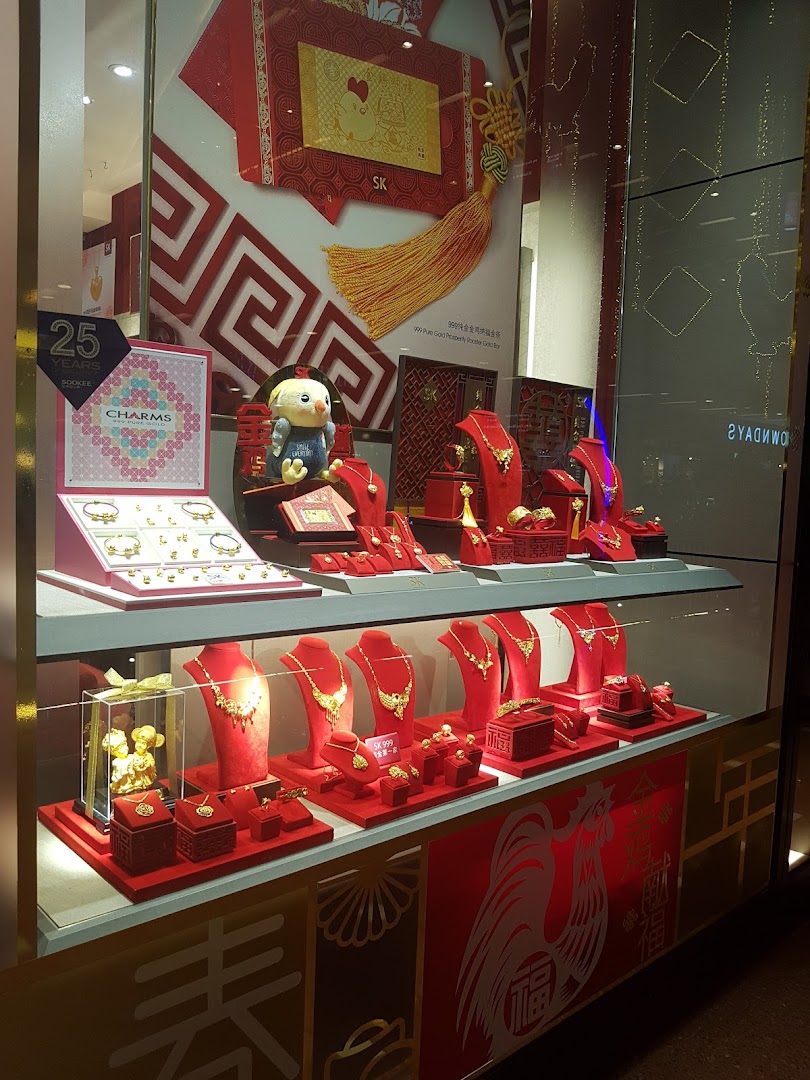 A vibrant SK Jewellery shop window display featuring gold jewellery, charms, and festive red decorations.
