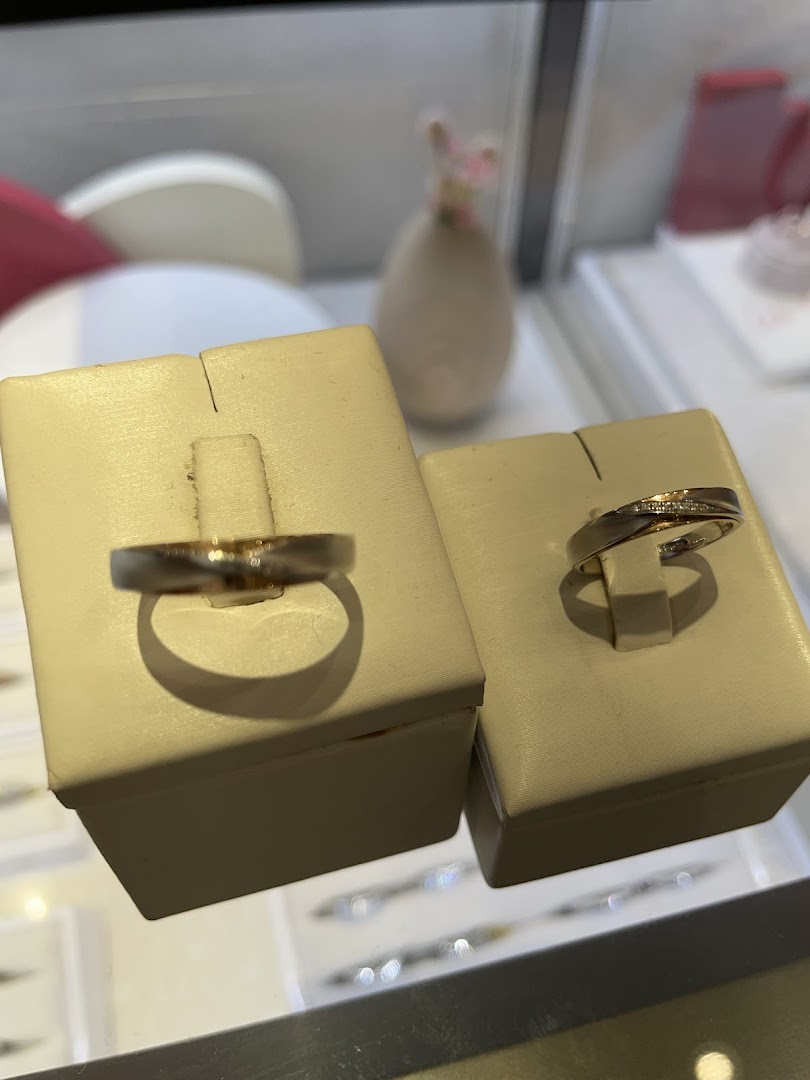 Two elegant rings, possibly wedding bands, displayed on stands in a jewellery shop.