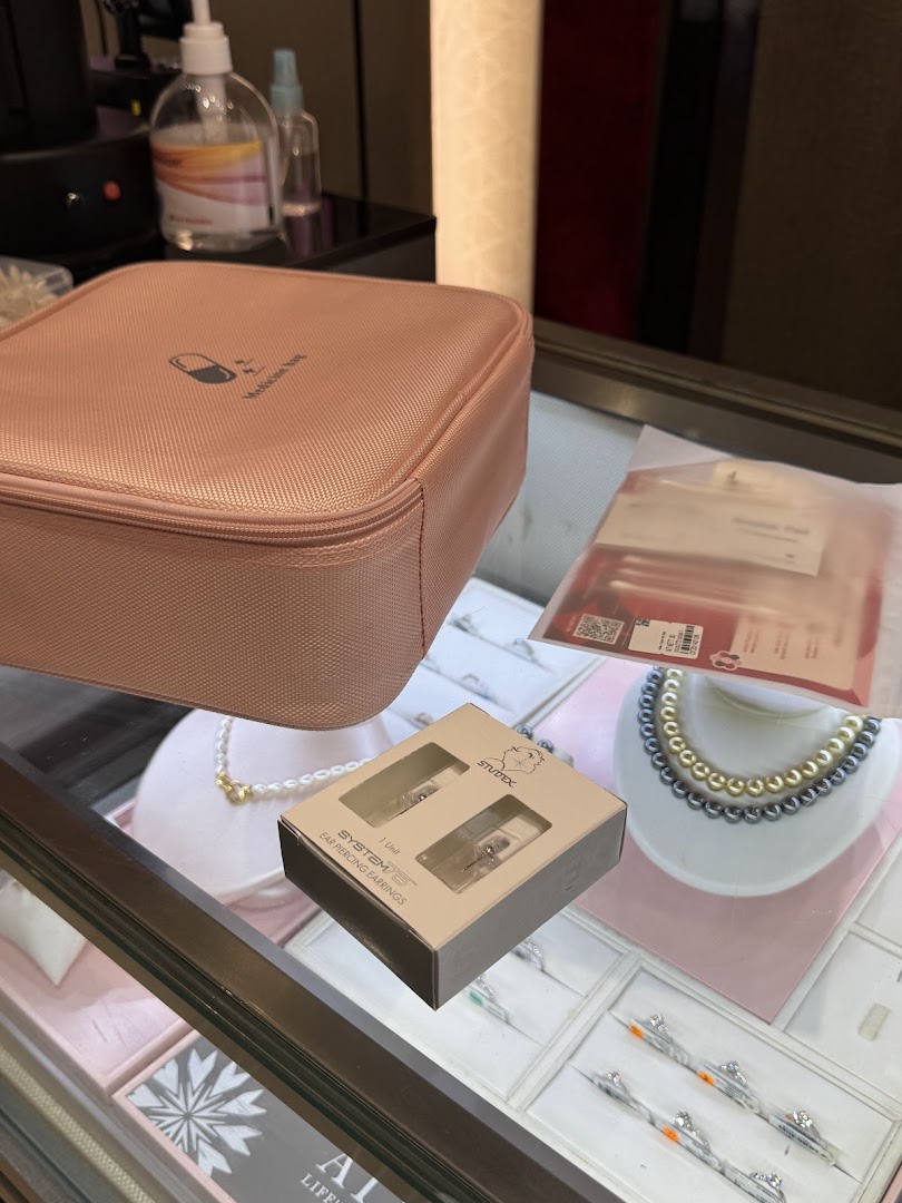 A close-up view of a jewelry display case featuring earrings, necklaces, and a pink pouch.