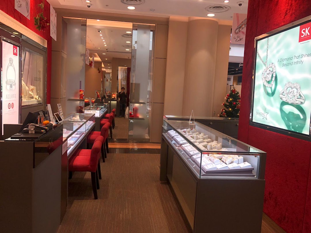 Interior view of SK Jewellery showcasing display cases, red seating, and a promotional screen.