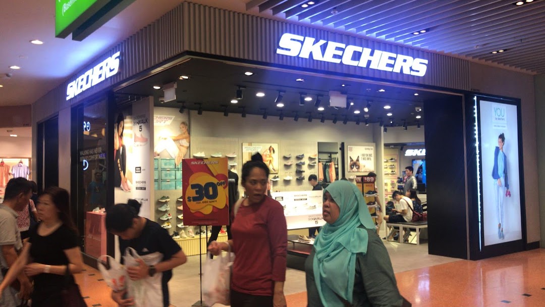 The brightly lit entrance of a Skechers footwear store in a bustling shopping mall.