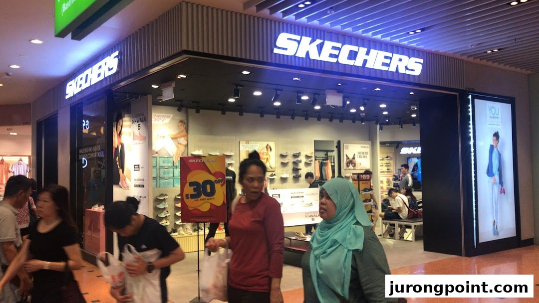 The brightly lit entrance of a Skechers footwear store in a bustling shopping mall.