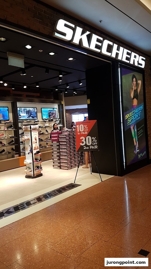 The entrance of a Skechers shoe store, featuring a prominent sale sign and interior view.