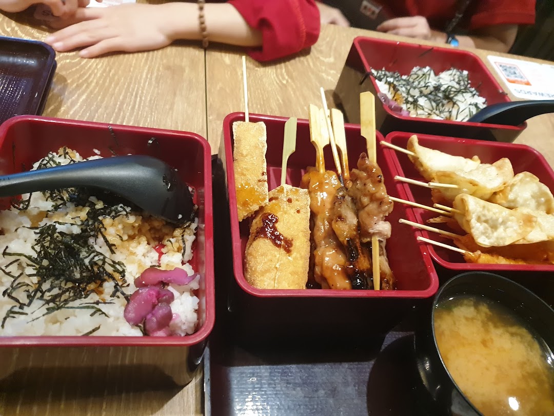 A close-up of various Japanese dishes, including rice bowls, skewers, dumplings, and miso soup.