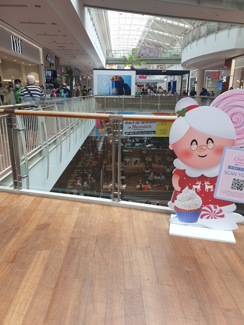 Interior view of a bustling multi-level shopping mall with various shops and a festive standee.