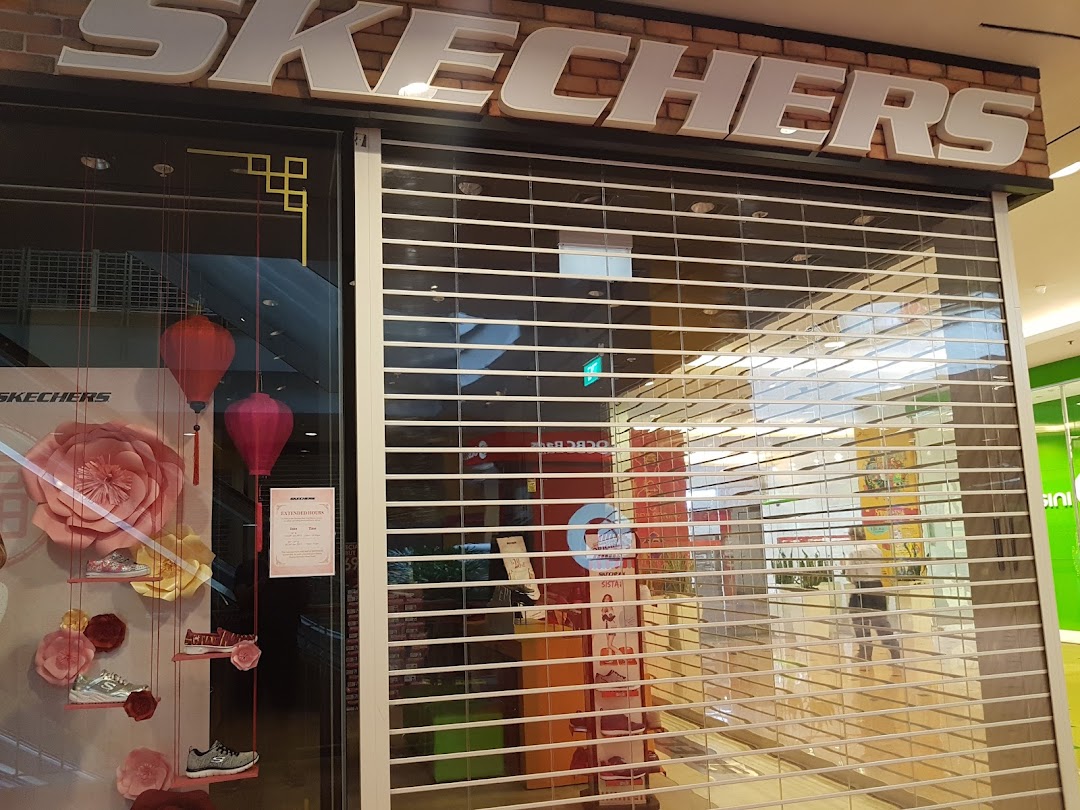 The Skechers shop front with a security shutter down, featuring a festive window display with shoes and lanterns.
