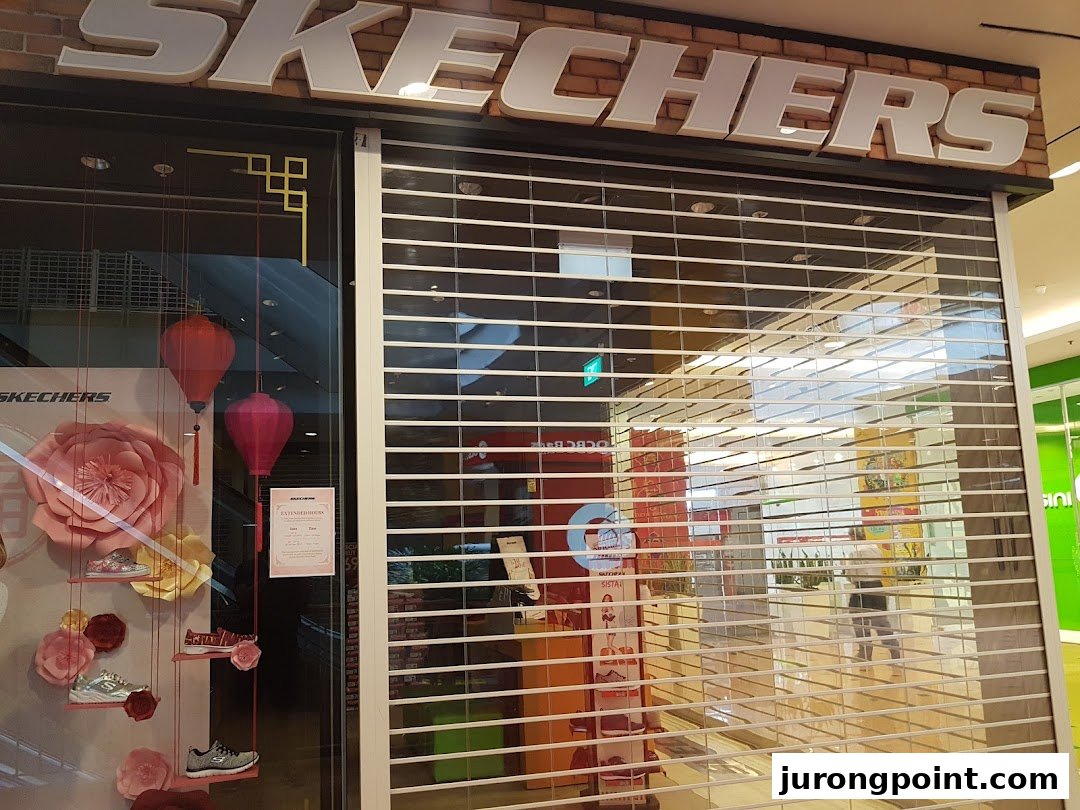 The Skechers shop front with a security shutter down, featuring a festive window display with shoes and lanterns.